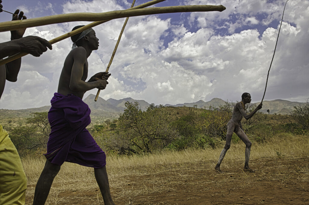 Tribal men carry long sticks